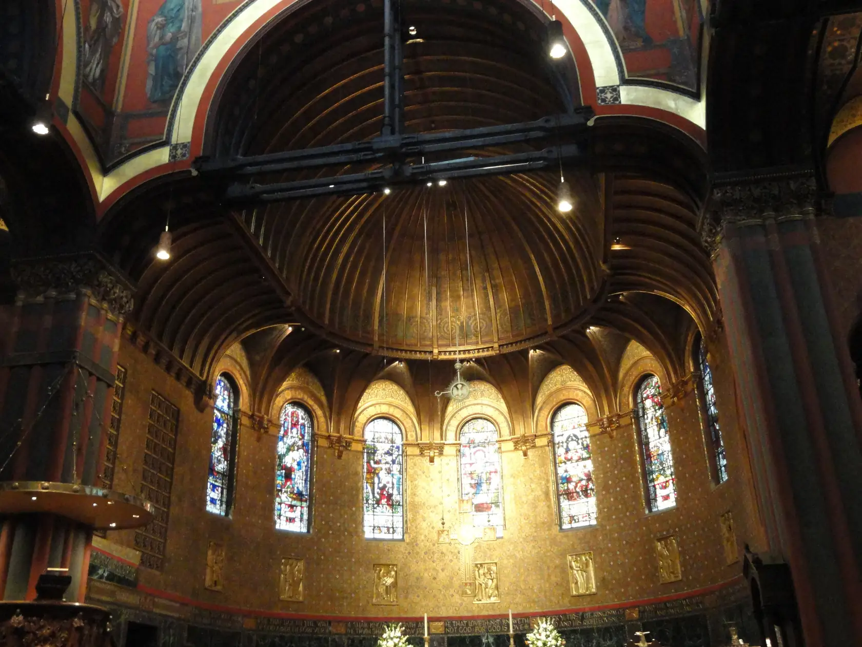 The chancel of Trinity Church, Boston, seen from the pews, with a painted wall, a cross, and the organ.