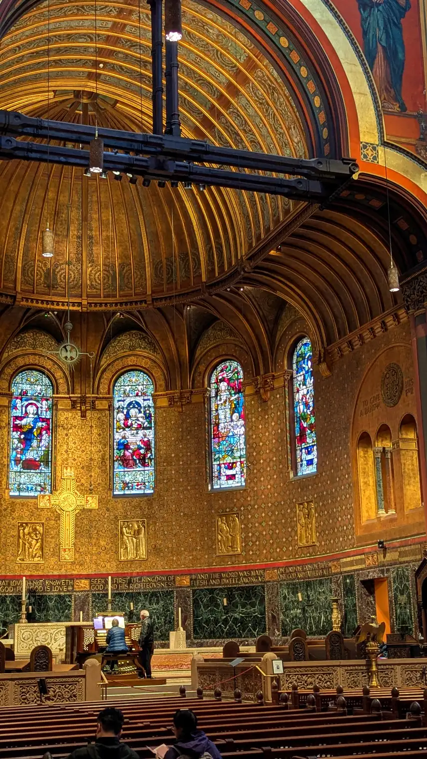 Looking up inside the central tower of Trinity Church, Boston: carved figures, patterned walls, and a ring of light.